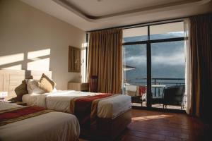 ein Hotelzimmer mit zwei Betten und einem großen Fenster in der Unterkunft Gateway Himalaya Resort in Ghanpokhara