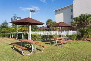 dwa stoły piknikowe z parasolami przed budynkiem w obiekcie Holiday Inn Express Hotel & Suites Fort Pierce West, an IHG Hotel w mieście Fort Pierce