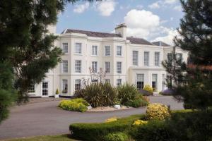 une grande maison blanche avec des arbres devant dans l'établissement Burnham Beeches Hotel & Spa, à Slough