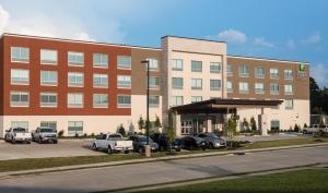 een groot gebouw met auto's geparkeerd op een parkeerplaats bij Holiday Inn Express & Suites Ruston, an IHG Hotel in Ruston