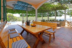 une table en bois et des bancs sur une terrasse dans l'établissement Unique seaside villa with pool, à Vela Luka