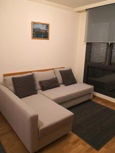 a couch sitting in a living room with a window at Apartamentos Chevere Azul con Garaje in Oviedo