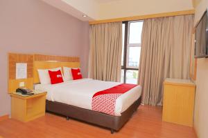 a bedroom with a bed with red pillows and a window at Houz Inn in Bintulu