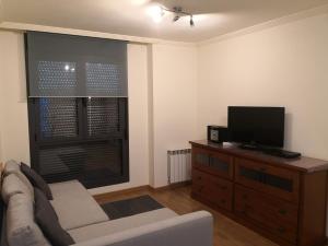a living room with a couch and a flat screen tv at Apartamentos Chevere Azul con Garaje in Oviedo