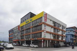 a large building with cars parked in a parking lot at Houz Inn in Bintulu