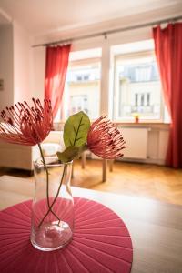 dos flores rojas en un jarrón sobre una mesa en Elegant Apartment Ordynacka, en Varsovia