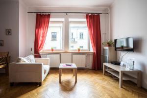 sala de estar con sofá y ventana con cortinas rojas en Elegant Apartment Ordynacka, en Varsovia