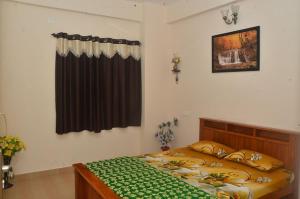 a bedroom with a large bed with a green blanket at Sri Vana Durga Service Apartment in Sringeri