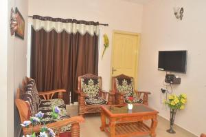 a living room with chairs and a table and a tv at Sri Vana Durga Service Apartment in Sringeri