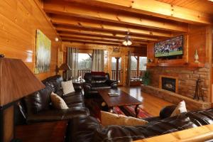 a living room with leather furniture and a fireplace at Ridgetop Theatre Lodge Cabin in Park Settlement