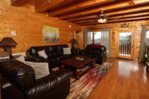 a living room with leather couches and a table at Ridgetop Theatre Lodge Cabin in Park Settlement