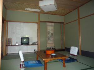 a living room with a table and a tv at Takao Kanko Hotel in Kyoto