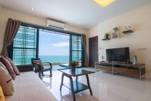 a living room with a television and a large window at Koh Sirey Beachfront Pool Villa in Phuket