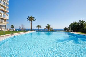 duży basen z palmami i oceanem w obiekcie PURO BEACH. Charming apartment with jacuzzi. w mieście Torremolinos