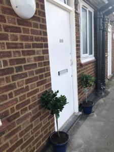 ein Backsteingebäude mit zwei Topfpflanzen neben einer Tür in der Unterkunft Super location 1min from metro 10min from Camden in London