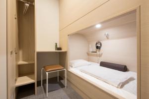 niewielka sypialnia z łóżkiem i krzesłem w obiekcie Grand Cabin Tenjin Minami w mieście Fukuoka