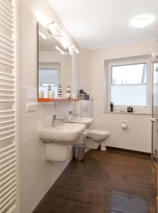 La salle de bains blanche est pourvue d'un lavabo et de toilettes. dans l'établissement Haus Südwester Herzmuschel, à Timmendorfer Strand