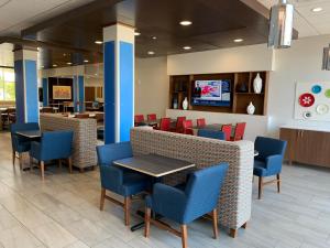 a waiting area with chairs and tables in a lobby at Holiday Inn Express & Suites Moore, an IHG Hotel in Moore