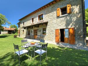 a table and chairs in front of a stone house at Apartment Azienda Agricola Piano Rosso-4 by Interhome in Marradi