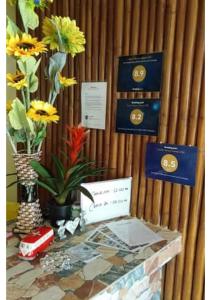 een tafel met bloemen en certificaten aan de muur bij Sea Breeze Beachfront Home and Cottages in San Juan