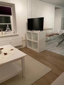 uma sala de estar com uma televisão de ecrã plano num armário branco em Citi Wohnung em Husum