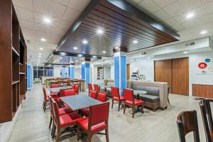 a restaurant with red chairs and tables and a bar at Holiday Inn Express & Suites - Coffeyville by IHG in Coffeyville