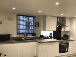 eine Küche mit weißen Schränken und einer Spüle und einem Fenster in der Unterkunft Daisy Cottage in Saint Monance + 5 Fotos