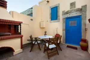 eine Terrasse mit einem Tisch, Stühlen und einer blauen Tür in der Unterkunft M-Cube Malona Village House near Lindos in Malona Village