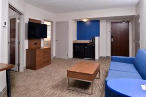 a living room with a blue couch and a tv at Holiday Inn Express & Suites Buffalo Downtown, an IHG Hotel in Buffalo