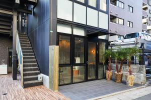 un bâtiment avec des portes en verre et des plantes en pot sur le trottoir dans l'établissement mizuka Daimyo 7 - unmanned hotel -, à Fukuoka