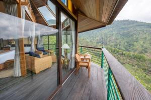 a room with a balcony with a bed and a desk at Munduk Heaven Luxury Villas in Munduk