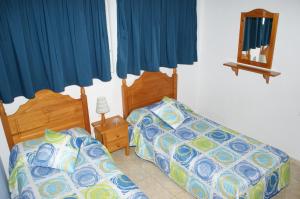 a bedroom with two beds and blue curtains at Apartamentos Teror - Gavias del Sol in Playa del Ingles +30 photos