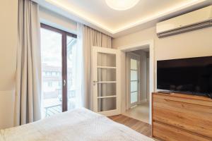 a bedroom with a large tv and a large window at Grand Apartments - Superior apartment in a luxury closed estate in Sopot