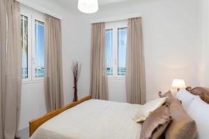 biała sypialnia z dużym łóżkiem i oknami w obiekcie Andriani Apartment w mieście Zakintos
