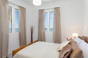 a white bedroom with a large bed with windows at Andriani Apartment in Zakynthos Town