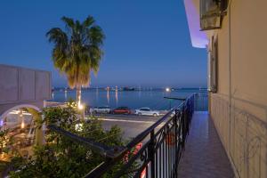 a balcony with a palm tree and a view of the water at Andriani Apartment in Zakynthos Town