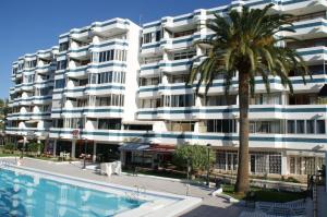 a building with a palm tree and a swimming pool at Apartamentos Teror - Gavias del Sol in Playa del Ingles