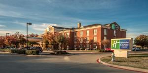a large brick building with a sign in front of it at Holiday Inn Express Hotel & Suites Plano West - Frisco by IHG in Plano