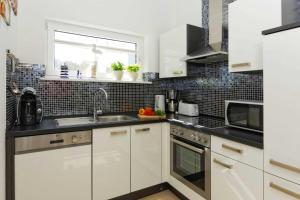 a kitchen with white cabinets and a sink at Lotsenstieg 03 in Ostseebad Karlshagen