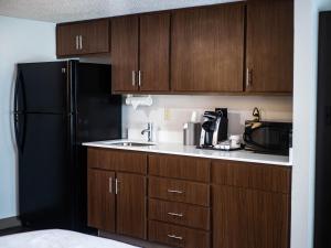 - une cuisine avec des placards en bois et un réfrigérateur noir dans l'établissement Holiday Inn Express & Suites Charlotte-Concord-I-85, an IHG Hotel, à Concord
