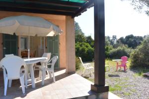 eine Terrasse mit einem Tisch, Stühlen und einem Sonnenschirm in der Unterkunft RUMANA 1- PROCHE PLAGE ET COMMERCES - ALERIA in Aléria