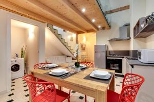 cocina y comedor con mesa de madera y sillas rojas en Arsenale Loft - Biennale, en Venecia