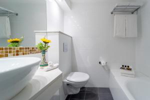 a white bathroom with a toilet and a sink at Prima Kings Hotel in Jerusalem