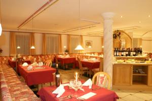 a restaurant with red tables and chairs and wine bottles at Hotel Akelei in Brunico