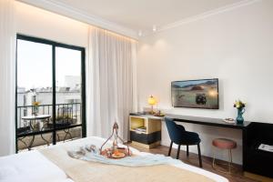 a bedroom with a bed and a desk and a balcony at Prima Kings Hotel in Jerusalem