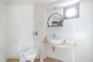 a white bathroom with a sink and a toilet at Tsolis Village in Lambírion