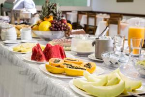 a table topped with plates of fruit and juice at Montblanc Hotel in Uberlândia