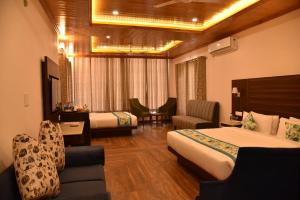 a hotel room with two beds and a couch at Mastiff Wildcrest Outer Dharamshala Near Chamunda Devi Temple in Pālampur