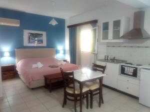 a bedroom with a bed and a table and a kitchen at Cristal Studios in Zóla