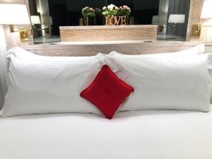 a red pillow on a bed with white pillows at Hotel Alla Posta in Saint Vincent